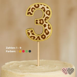 Könnte beinhalten: Ein Kuchenaufsatz aus Holz mit der Zahl drei und einem Leopardenmuster. Die Zahl ist mit goldenem Glitzer umrandet und auf einem Holzstab befestigt. Der Text "Zahlen: 1-9 Farben:" ist sichtbar.
