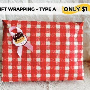 May include: A gift wrapped in red and white checkered paper, adorned with a pink ribbon and a decorative cake-shaped embellishment. The text "GIFT WRAPPING - TYPE A" is visible at the top.