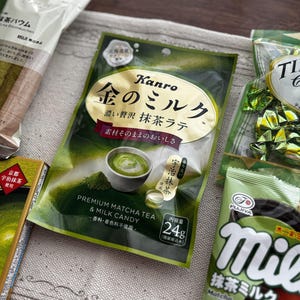 May include: An assortment of Japanese matcha-flavored snacks, including matcha latte candy, tiramisu chocolate, and matcha-flavored biscuits. The packaging features green and gold colors, with Japanese text.