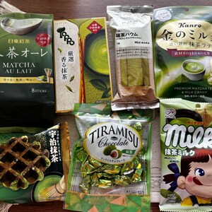 May include: Assortment of Japanese matcha-flavored snacks and treats, including matcha au lait, matcha baumkuchen, matcha candy, and tiramisu chocolate. The packaging features green and gold colors, with Japanese text and illustrations.