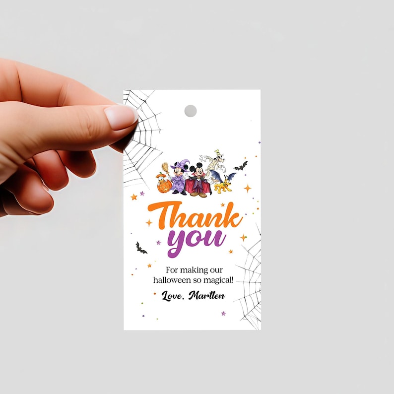 May include: A rectangular white gift tag featuring a Halloween theme with Disney characters in costumes, spider web illustrations, and orange and purple text that reads: Thank you For making our halloween so magical! Love, Martten.