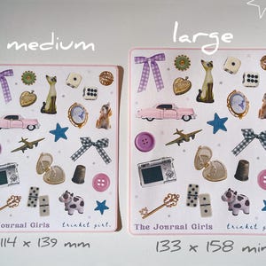 May include: Two pink and white sticker sheets with various images, including a car, a cat, a camera, a key, dominoes, and a cow. The text "The Journal Girls" and "trinket girl." is printed on each sheet. The sheet on the left measures 114 x 139 mm and the sheet on the right measures 133 x 158 mm.