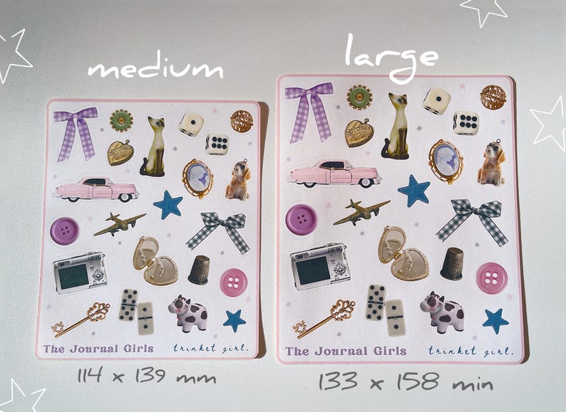 May include: Two pink and white sticker sheets with various images, including a car, a cat, a camera, a key, dominoes, and a cow. The text "The Journal Girls" and "trinket girl." is printed on each sheet. The sheet on the left measures 114 x 139 mm and the sheet on the right measures 133 x 158 mm.