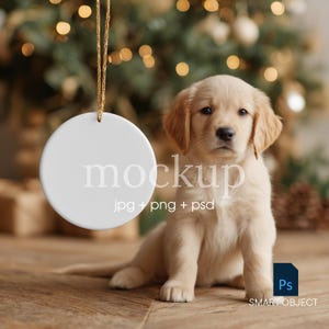 May include: A white, round Christmas ornament hangs from a gold string, with the word "mockup" printed on it. A golden retriever puppy sits on a wooden surface in front of a Christmas tree with bokeh lights. The image includes the text "jpg + png + psd" and a Photoshop icon.