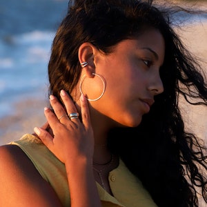 May include: Silver hoop earrings and a silver ring.