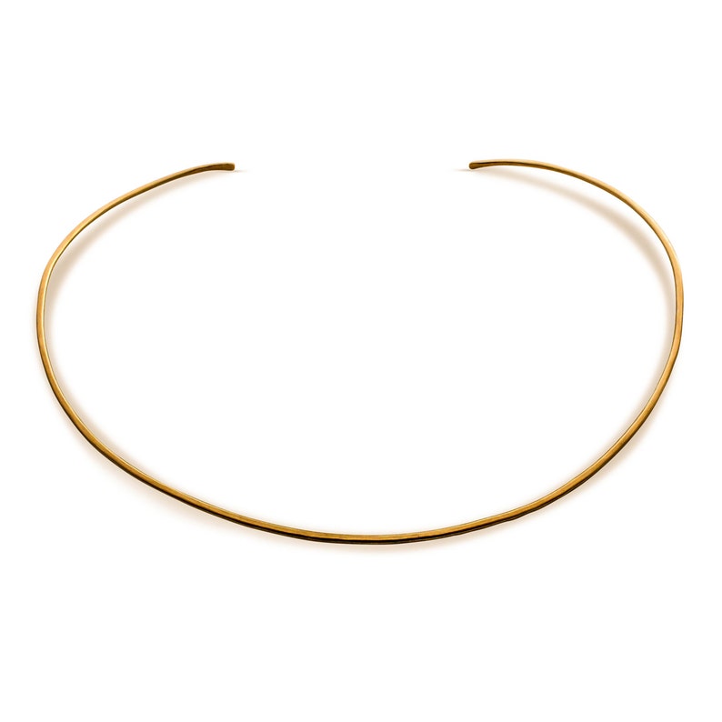 May include: A simple gold choker necklace, a thin band of metal that sits close to the neck.