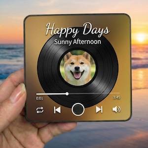 May include: Square coaster with a golden gradient background featuring a Shiba Inu dog inside a vinyl record design. The text "Happy Days Sunny Afternoon" is displayed above the record. Playback controls are visible at the bottom.