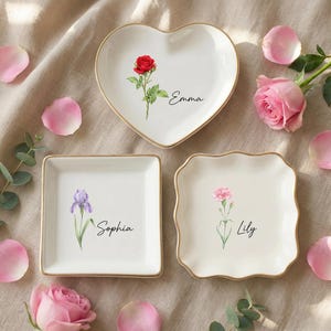 Könnte beinhalten: Ein Set aus drei Keramikbechern mit gesprenkelter, matter Oberfläche. Die Becher sind in Creme-, Hellgrau- und Dunkelgrautönen gehalten. Jeder Becher hat ein schlichtes, minimalistisches Design, ideal für Kaffee oder Tee.