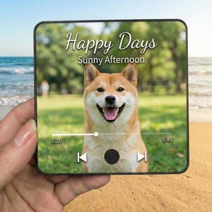May include: A digital screen displays a Shiba Inu dog with a happy expression, set against a sunny outdoor backdrop. The screen shows the text "Happy Days, Sunny Afternoon" and a music player interface.