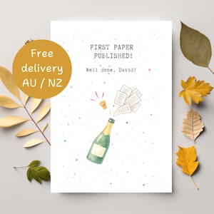 Op de afbeelding: Een wenskaart met een aquarel illustratie van een champagnefles die ontploft, met papieren die eruit vliegen. De tekst luidt: "FIRST PAPER PUBLISHED! Well done, David!" en is omgeven door kleurrijke confetti.