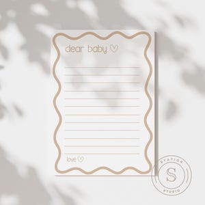 Może przedstawiać: Biała karta papiernicza z falistą, jasnobrązową obw&oacute;dką. Na karcie wydrukowano słowa "dear baby" i "love" wraz z symbolem serca. Poziome linie wypełniają środek karty.
