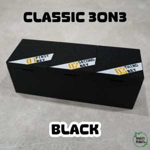 Puede incluir: Caja de almacenamiento negra con tres compartimentos, cada uno etiquetado con un número y la palabra "BEY". El texto "CLASSIC 3ON3" está encima de la caja y "BLACK" debajo. La caja tiene un acabado mate.