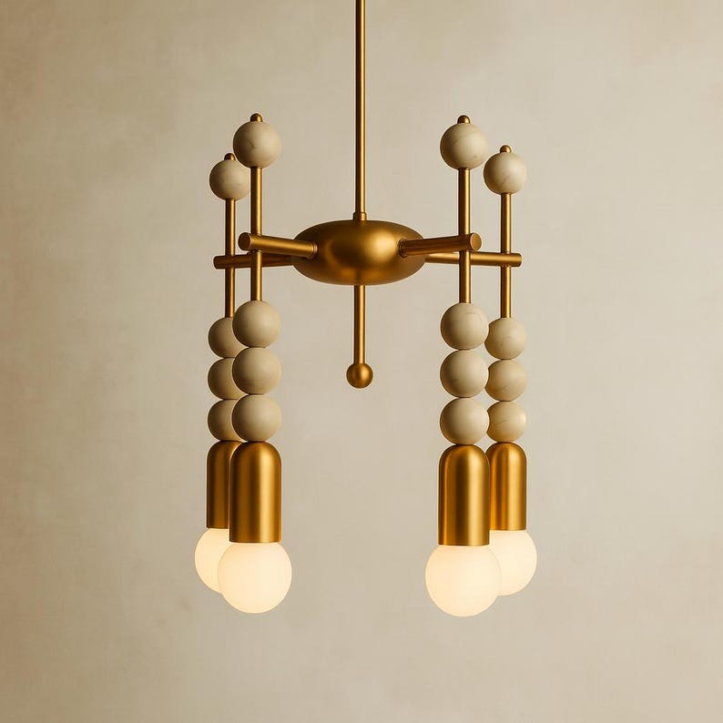 May include: A modern chandelier with a gold finish and a unique design. The fixture features multiple arms with cream-colored spheres and globe-shaped light bulbs. The overall aesthetic is a blend of mid-century modern and contemporary styles.