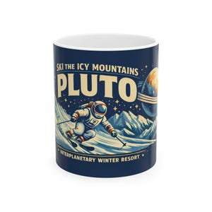 May include: A ceramic mug with a dark blue background features an astronaut skiing down a snowy mountain. The text reads "SKI THE ICY MOUNTAINS PLUTO" and "INTERPLANETARY WINTER RESORT". A planet with rings is in the background.