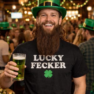 May include: A person wearing a green top hat and a black t-shirt that says "LUCKY FECKER" with a green shamrock. The person is holding a pint of green beer. The background shows a crowded bar setting.
