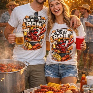 Puede incluir: Dos personas con camisetas blancas con un gráfico de un cangrejo de dibujos animados y el texto "LET THE GOOD TIMES BOIL". Sostienen bebidas y sonríen. Se está preparando una ebullición de cangrejos con maíz y salchichas.