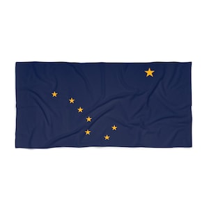 Puede incluir: Un textil rectangular azul marino con la bandera de Alaska. El diseño de la bandera incluye ocho estrellas doradas dispuestas en forma de la Osa Mayor y la Estrella Polar. El textil es probablemente una manta o una toalla.