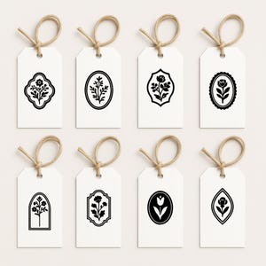 May include: Eight white gift tags with black floral designs. Each tag has a different floral motif, including a tulip, a single flower, and a bouquet of flowers. The tags are tied with twine.