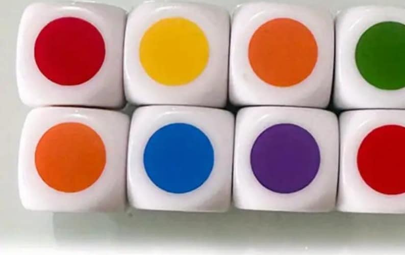 May include: Eight white dice with a single colored circle on each face. The colors are red, yellow, orange, green, orange, blue, purple, and red. The dice are arranged in two rows of four.