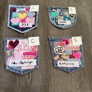 May include: Four denim pocket patches with fabric and embroidery embellishments. Patch A has hearts and the number 333. Patch B has the word "Hope". Patch C says "New Beginnings". Patch D says "Balance".