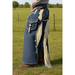 May include: Blue leather chaps with cream-colored fringe and accents. The chaps feature a pocket, decorative stitching, and silver-tone buttons. A brown leather belt and cowboy boots complete the Western look.