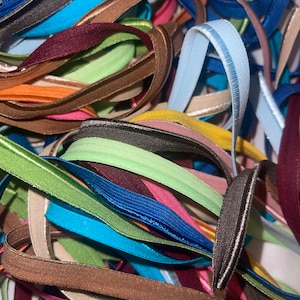 May include: A pile of colorful elastic straps with different colors and textures. The straps are folded and arranged in a random pattern.