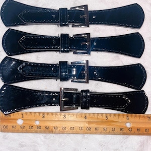 May include: Four black leather straps with silver buckles. The straps are approximately 4 inches long.