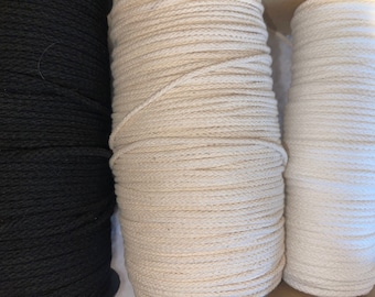 May include: Three spools of cord arranged side by side. The left spool is black, the center spool is a natural beige, and the right spool is white. Each spool is tightly wound with a continuous length of braided cord, showing a consistent texture.