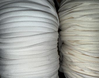 May include: Two spools of white elastic cord, one is a brighter white and the other is a creamier white.