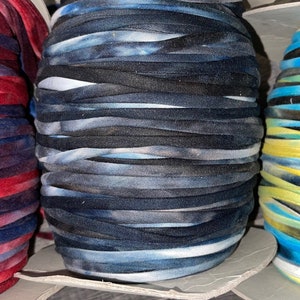 May include: Three spools of tie-dye yarn in red, blue, and yellow color combinations. The yarn is wound tightly and is ready to be used for crafting projects.