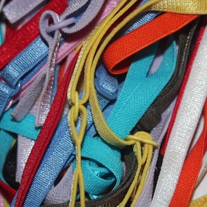May include: A close-up of a collection of colorful elastic straps and loops in various colors, including red, blue, yellow, orange, and white. The straps are made of a woven material and are used for various crafting and sewing projects.