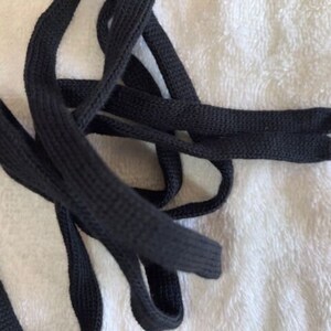 May include: Black shoelaces with silver metal aglets. The shoelaces are made of a thick, woven material.