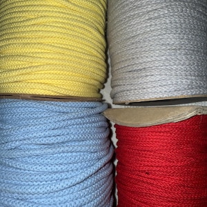 May include: Four spools of cotton rope in different colors: yellow, gray, light blue, and red.