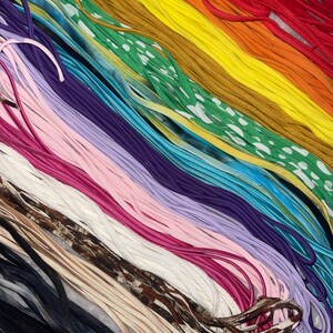 May include: A collection of colorful shoelaces in various shades, including red, orange, yellow, green, blue, purple, pink, and brown. Some laces have patterns, such as polka dots and camouflage. The laces are arranged in a diagonal pattern.