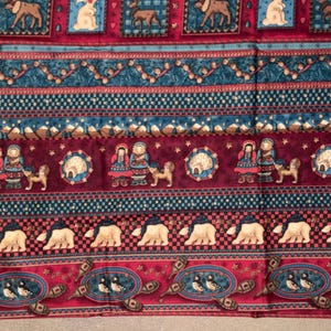 May include: A patterned fabric featuring horizontal bands with illustrations of moose, rabbits, igloos, people in winter clothing, polar bears, and puffins. The design incorporates deep red, blue, and white colors with geometric borders.