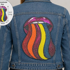 May include: A blue denim jacket featuring a large, colorful sequined patch on the back depicting lips with a rainbow tongue. The patch measures 12.5 inches long by 9 inches wide, as indicated by the circular graphic in the upper left corner.
