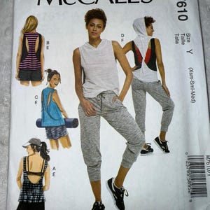 May include: McCall's sewing pattern M7610. The pattern features illustrations of athletic wear, including a sleeveless hoodie, shorts, and joggers. The cover shows a woman in a sleeveless hoodie and joggers. The pattern includes size Y (Xsm-Sml-Med).