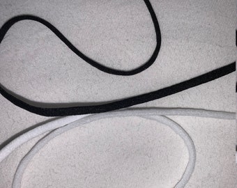 May include: Two pieces of elastic cord, one black and one white, are laid out on a white fabric surface.