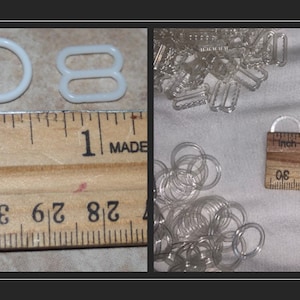 May include: An image showcasing various bra-making supplies. The image includes white plastic rings and sliders, along with clear plastic rings, hooks, and sliders. A wooden ruler is used to measure the items. The white rings are approximately 1 inch in diameter.