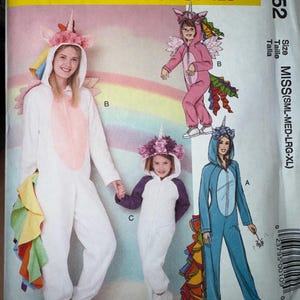 May include: McCall's Costumes pattern M7852 featuring unicorn-themed jumpsuits in white, pink, and blue. The costumes have attached hoods with unicorn horns and colorful tails. The pattern includes sizes for Misses, Small, Medium, Large, and Extra Large.