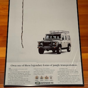May include: A white Land Rover Defender 110 is shown against a white background. The vehicle has a roof rack and is a popular choice for off-roading. The text "LAND ROVER DEFENDER 110" is displayed below the vehicle.