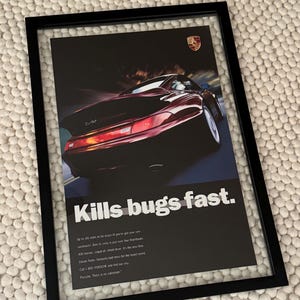 May include: Framed print featuring a red Porsche sports car speeding on a track. The image includes the text "Kills bugs fast." and additional details about the car's performance. The Porsche logo is visible.