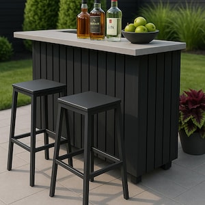 Puede incluir: Barra exterior con encimera gris y base de listones negros. Dos taburetes negros están frente a la barra. Tres botellas de licor y un cuenco de manzanas verdes están sobre la barra. La barra está en un patio.