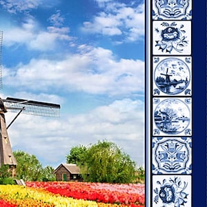 May include: A blue and white Delftware jug filled with colourful tulips sits on a wooden table in front of a field of tulips and a windmill in the distance. The jug is decorated with floral designs and has a blue and white border.