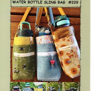 Könnte beinhalten: Drei Wasserflaschen-Umhängetaschen mit verschiedenen Mustern und Farben. Die Taschen haben eine Reißverschlusstasche und verstellbare Träger. Die Oberseite der Taschen weist eine Vielzahl von Mustern auf, darunter Bienen, Blumen und geometrische Designs. Der Text "SUZANNE'S ART HOUSE WATER BOTTLE SLING BAG #229" steht oben.