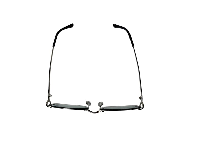 May include: A pair of silver-framed sunglasses with dark gray lenses. The sunglasses are closed and the arms are extended outward.