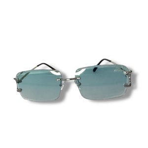 May include: Silver frame sunglasses with light blue lenses. The sunglasses have a square shape and a sleek design.