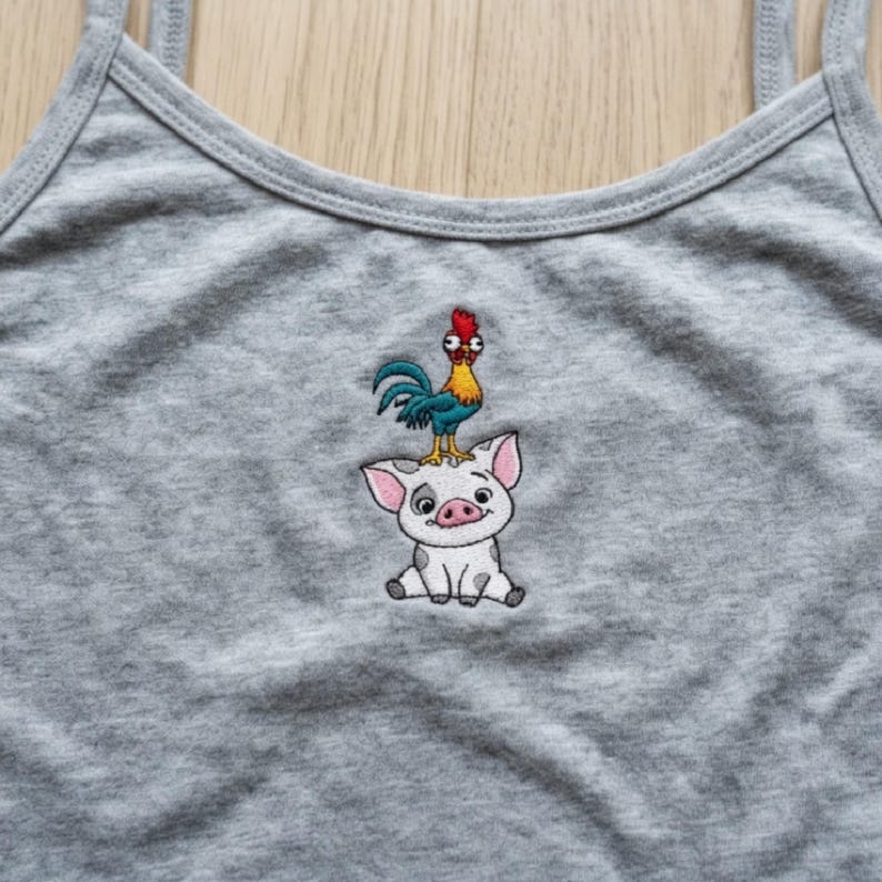 May include: A gray tank top with thin straps. The tank top features an embroidered design of a cartoon pig with a rooster on its head. The rooster has blue, yellow, and red coloring. The pig is white with pink ears and a smiling face.