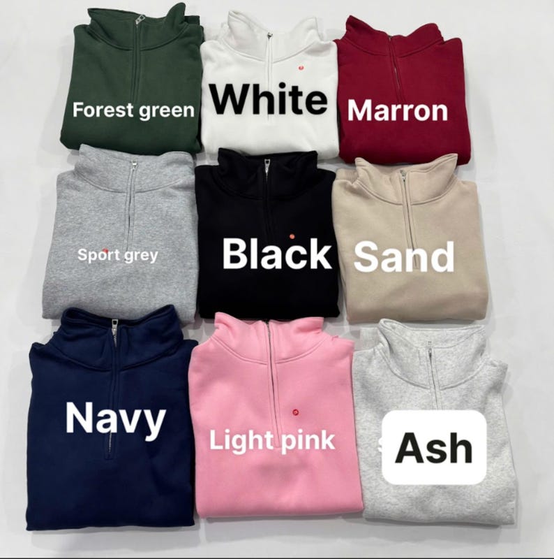 May include: A collection of nine quarter-zip sweatshirts in various colors, including forest green, white, maroon, sport grey, black, sand, navy, light pink, and ash. Each sweatshirt has a zipper and the color name is displayed on the front.