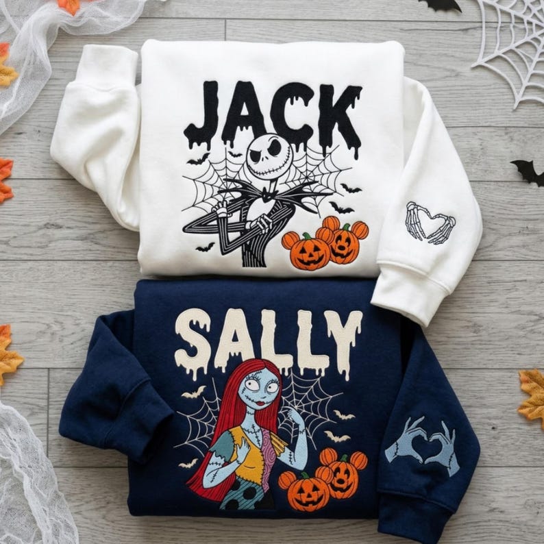 May include: A white sweatshirt featuring Jack Skellington, spiderwebs, bats, and orange pumpkins with the text JACK, plus a sleeve print of skeleton hands forming a heart. A navy blue sweatshirt featuring Sally, spiderwebs, bats, and orange pumpkins with the text SALLY, plus a sleeve print of stitched hands forming a heart.